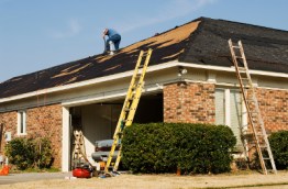 a man laboring at removing a tornado damaged roof.